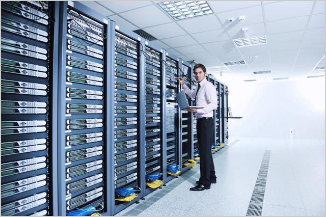 businessman with laptop in network server room